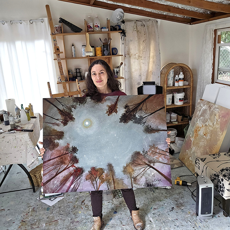 Cedar Lee in art studio with her painting "Moonrise"